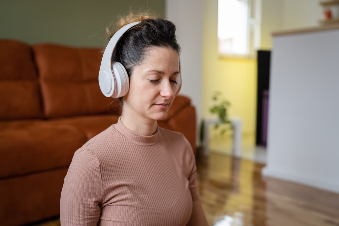Woman with eyes closed listening with headphones during mindful meditation